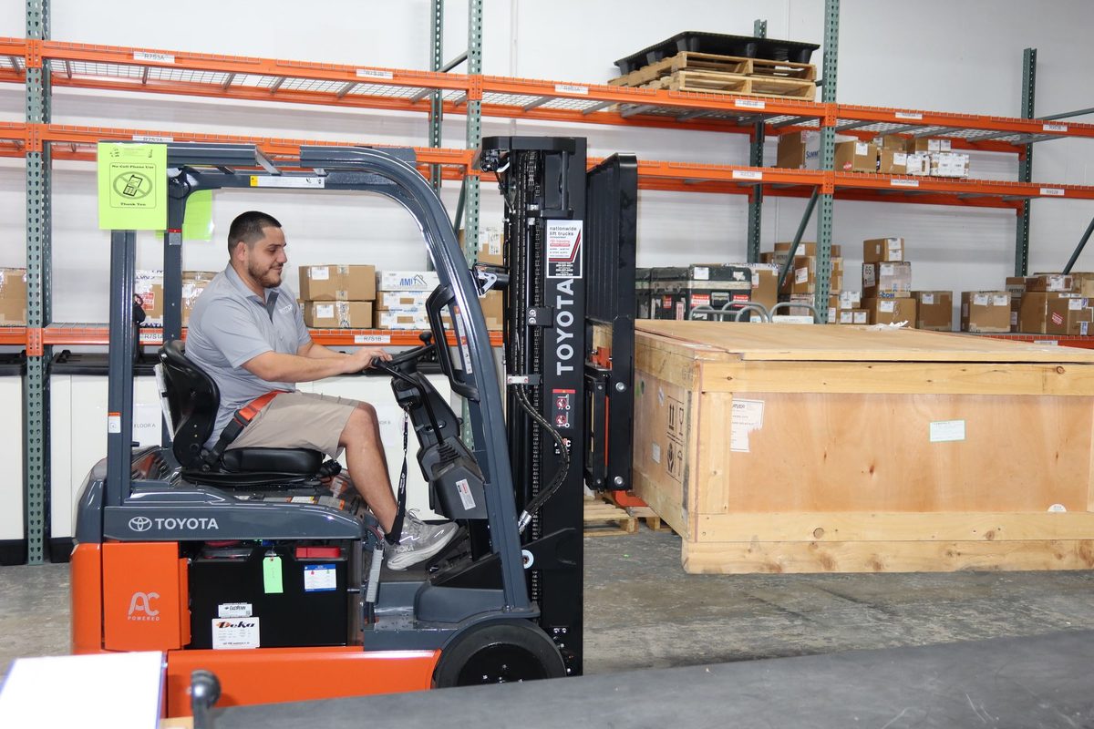 Julian Robinson moving a crated part with a forklift in the Skytop Aero warehouse